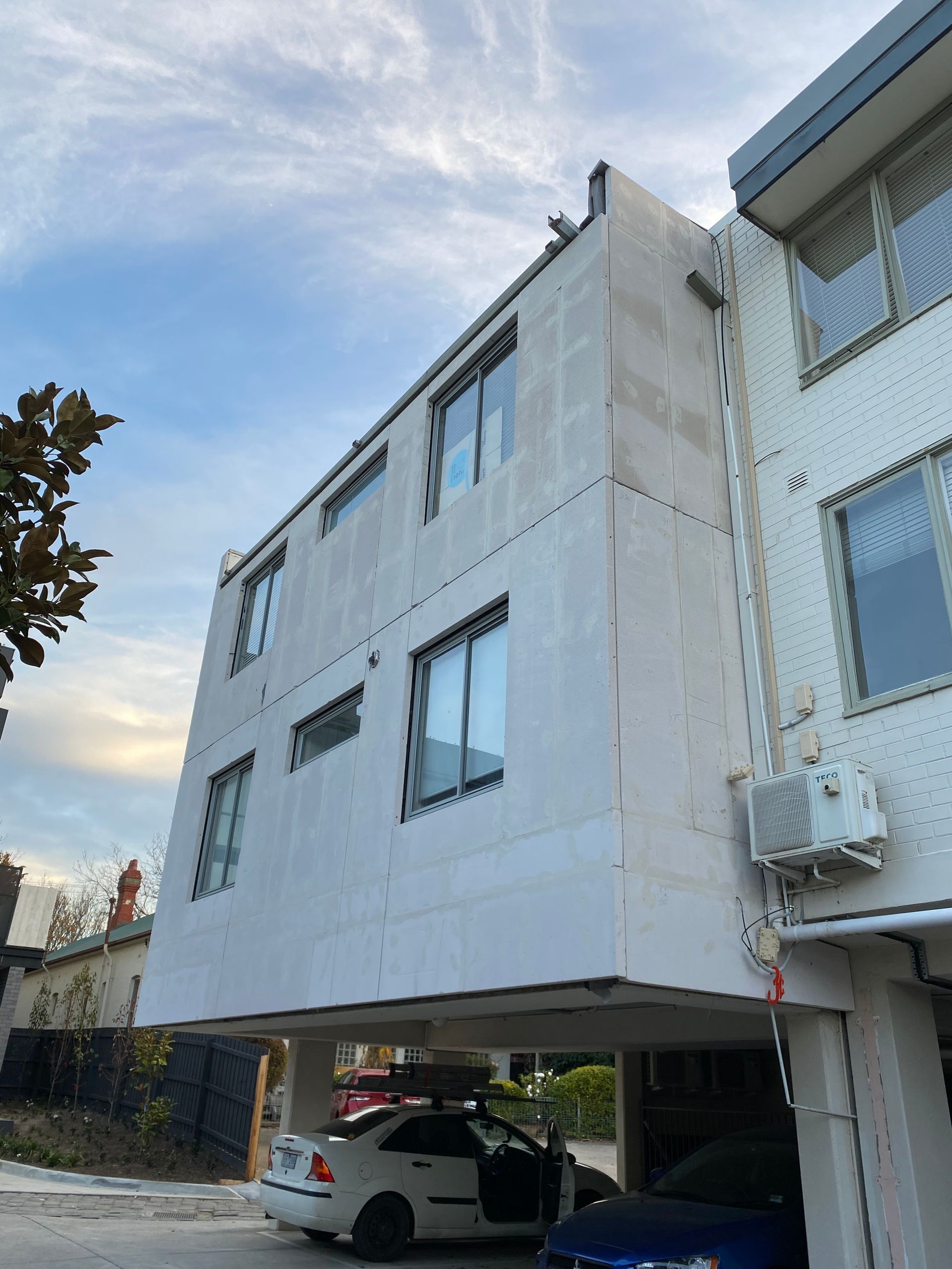 A white building with a car parked underneath it