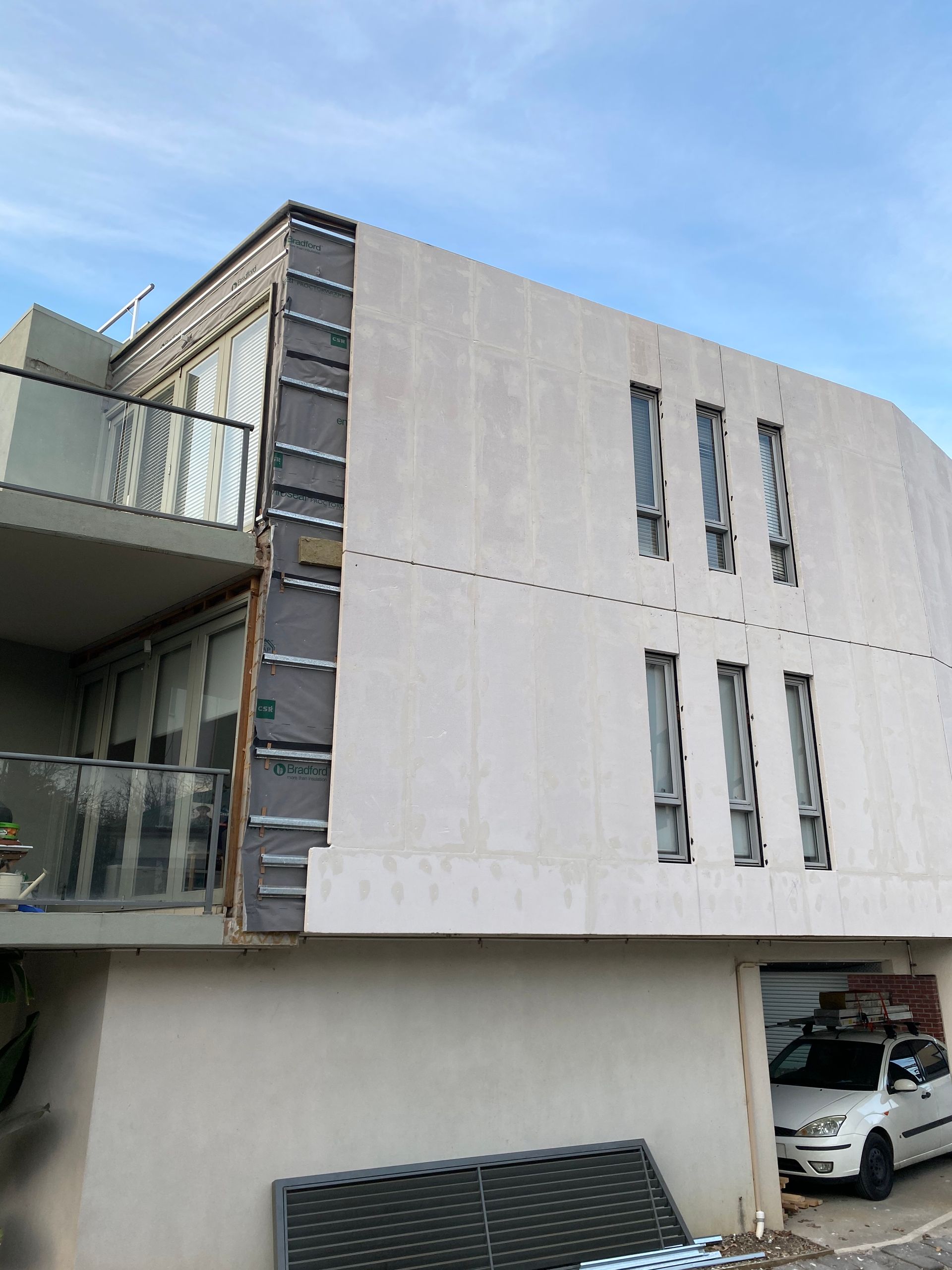 A white car is parked in front of a large building