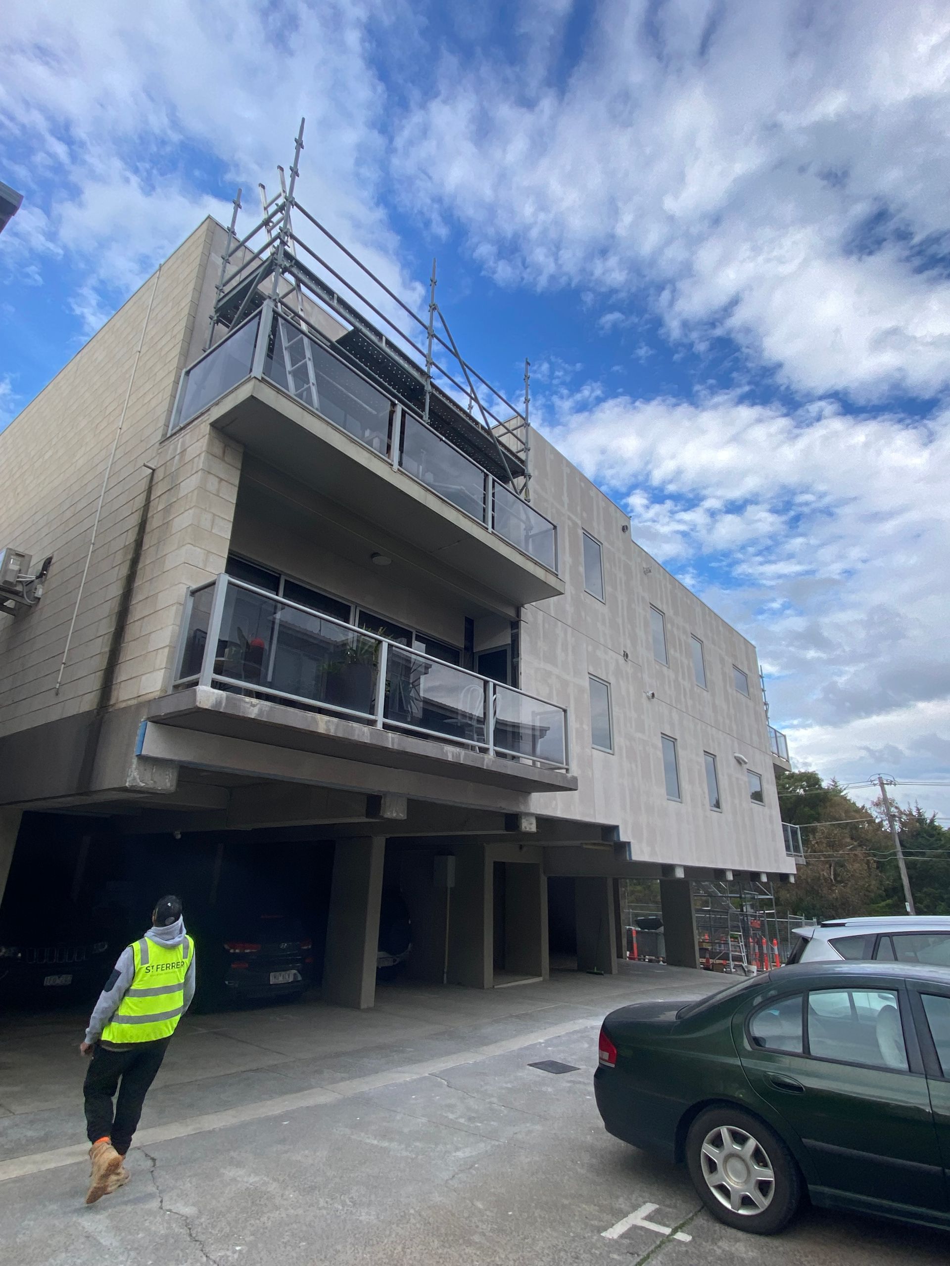 A man in a yellow vest is walking in front of a building