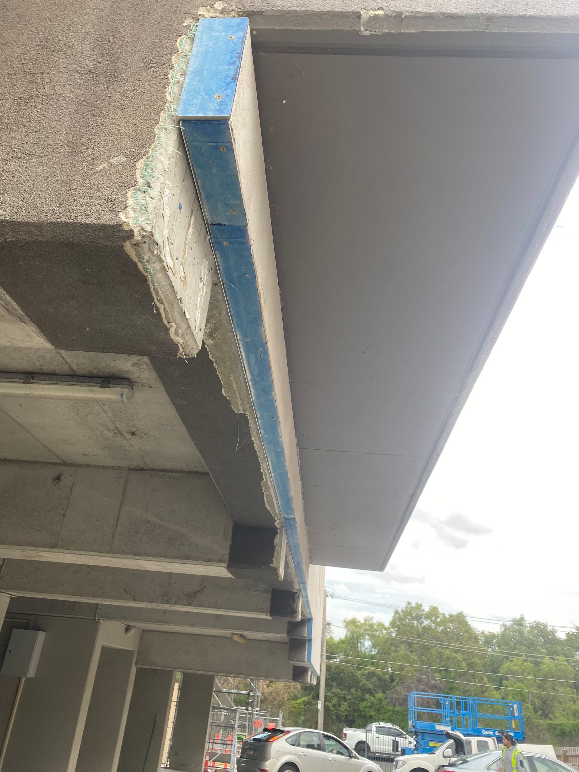 A roof of a building with cars parked underneath it.