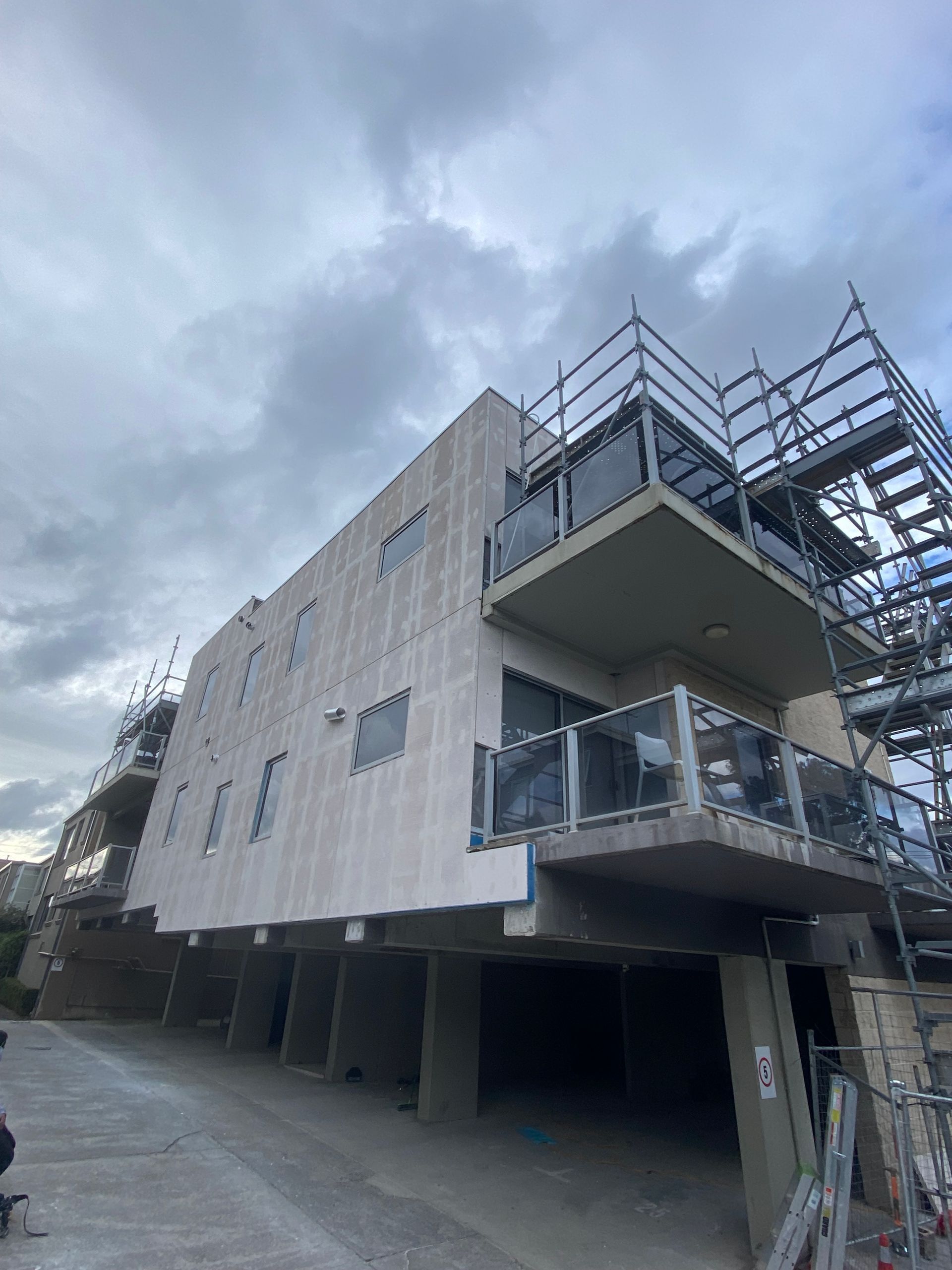 A large building under construction with a balcony and stairs.