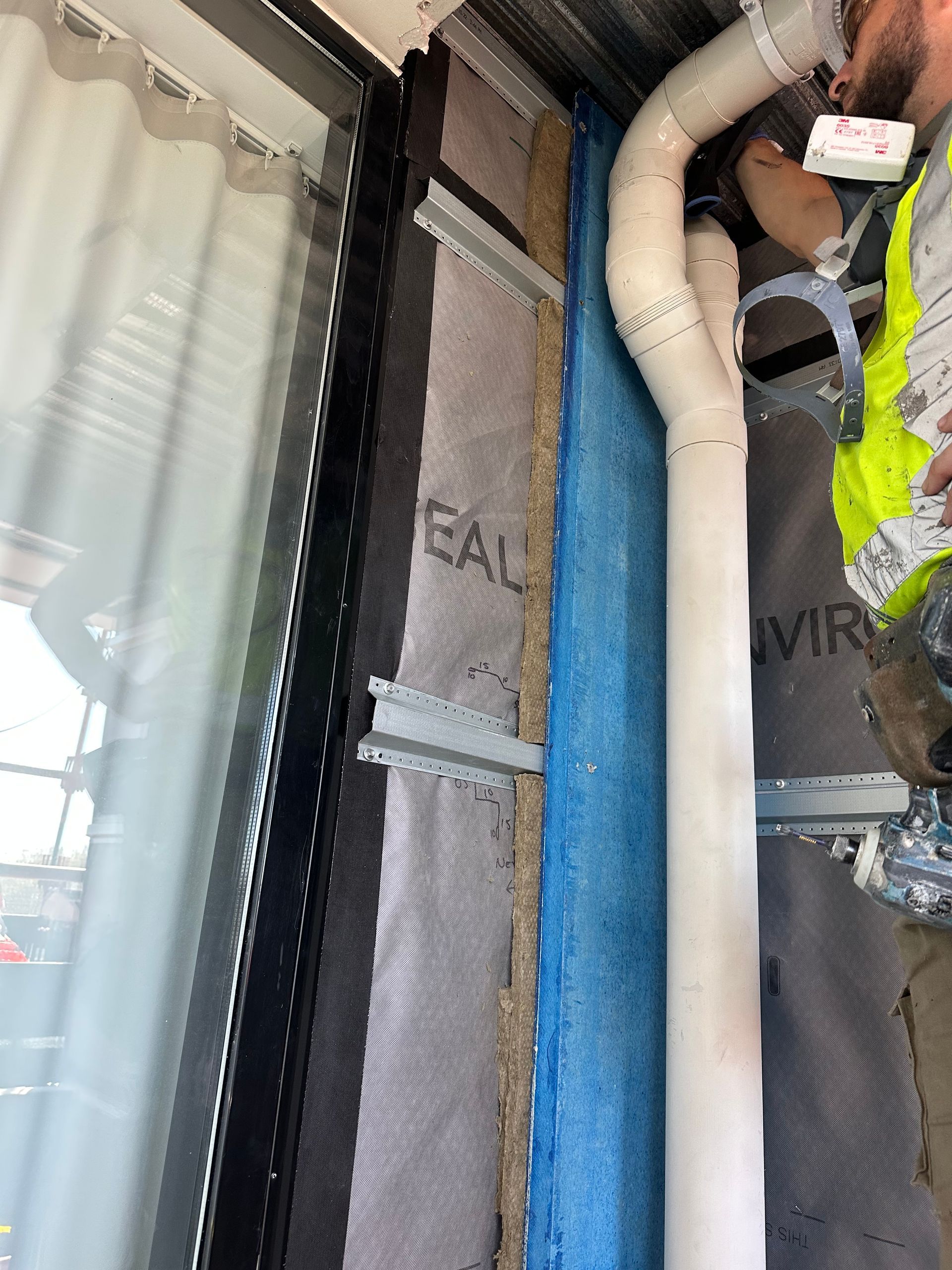 A man in a yellow vest is working on a building