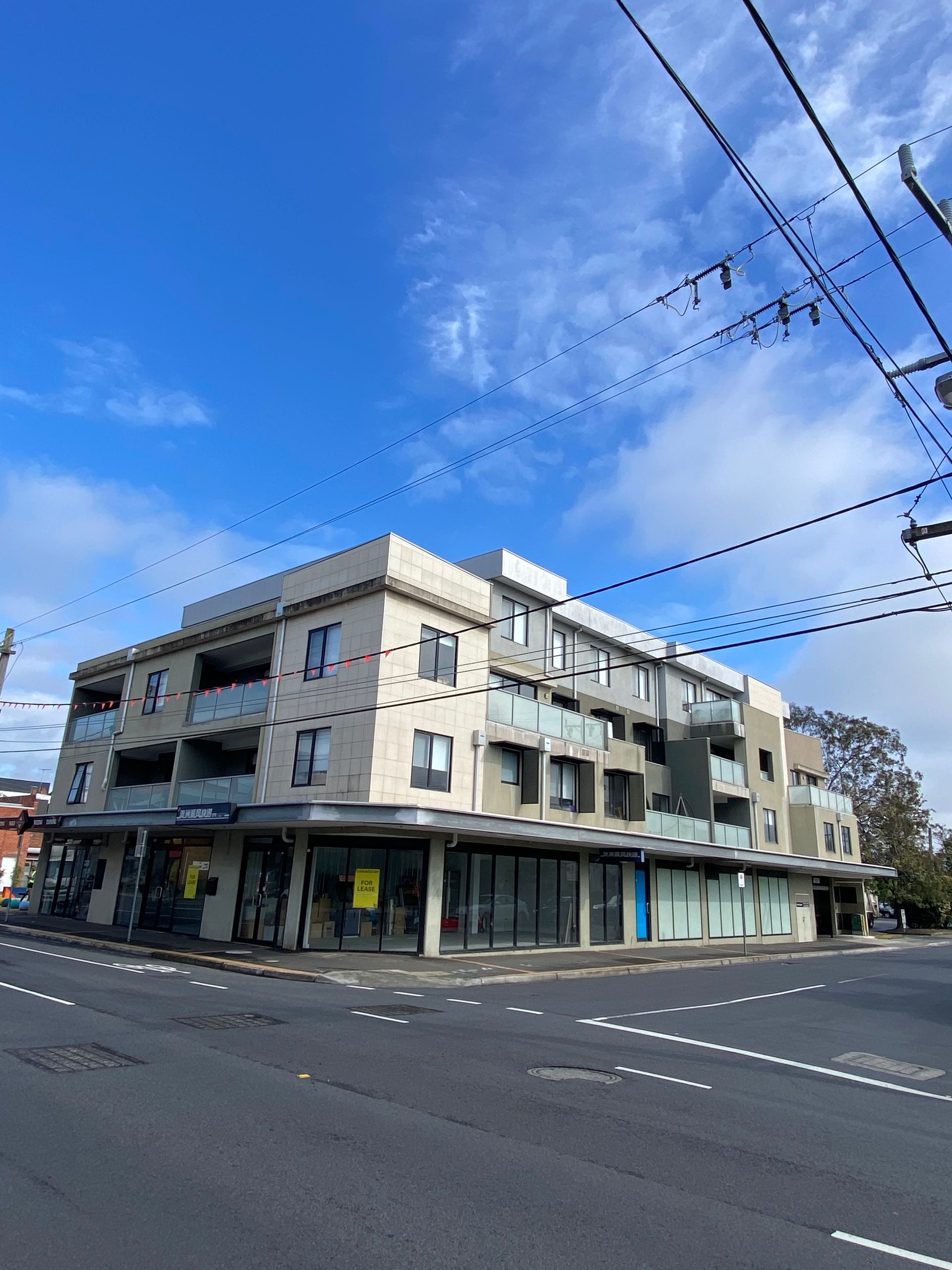 A large apartment building is sitting on the corner of a street.