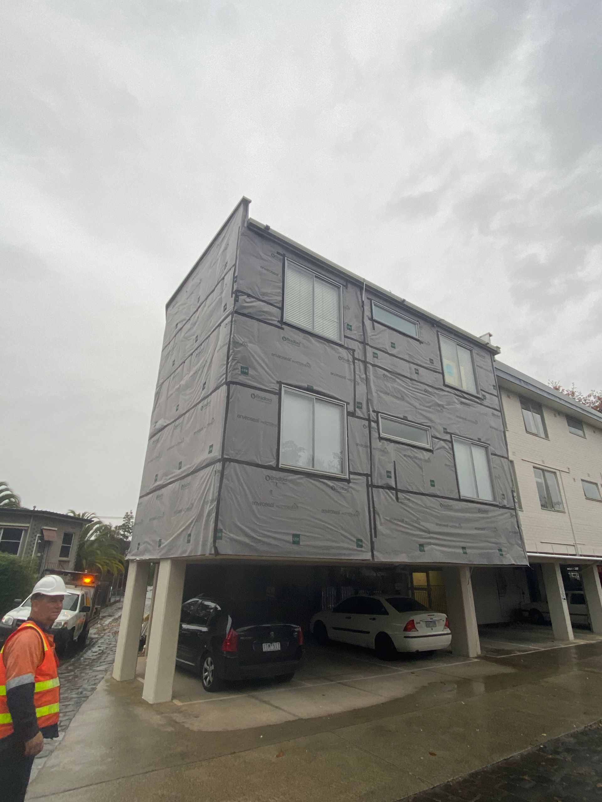 A man in a hard hat stands in front of a building