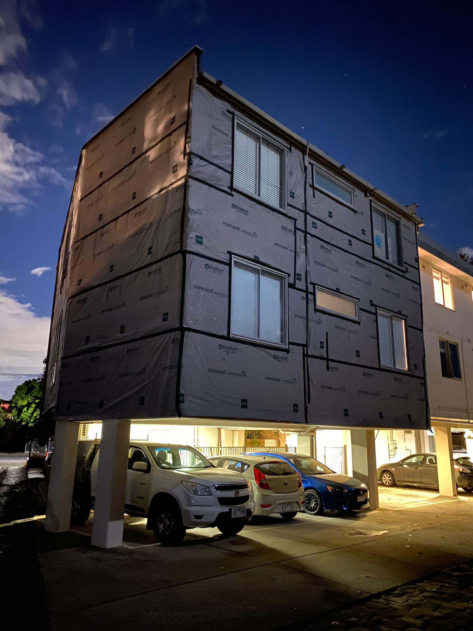 A building with cars parked underneath it at night