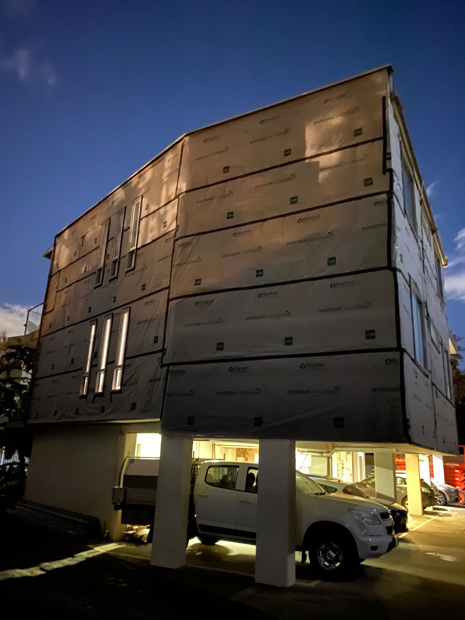 A white truck is parked in front of a building that is under construction