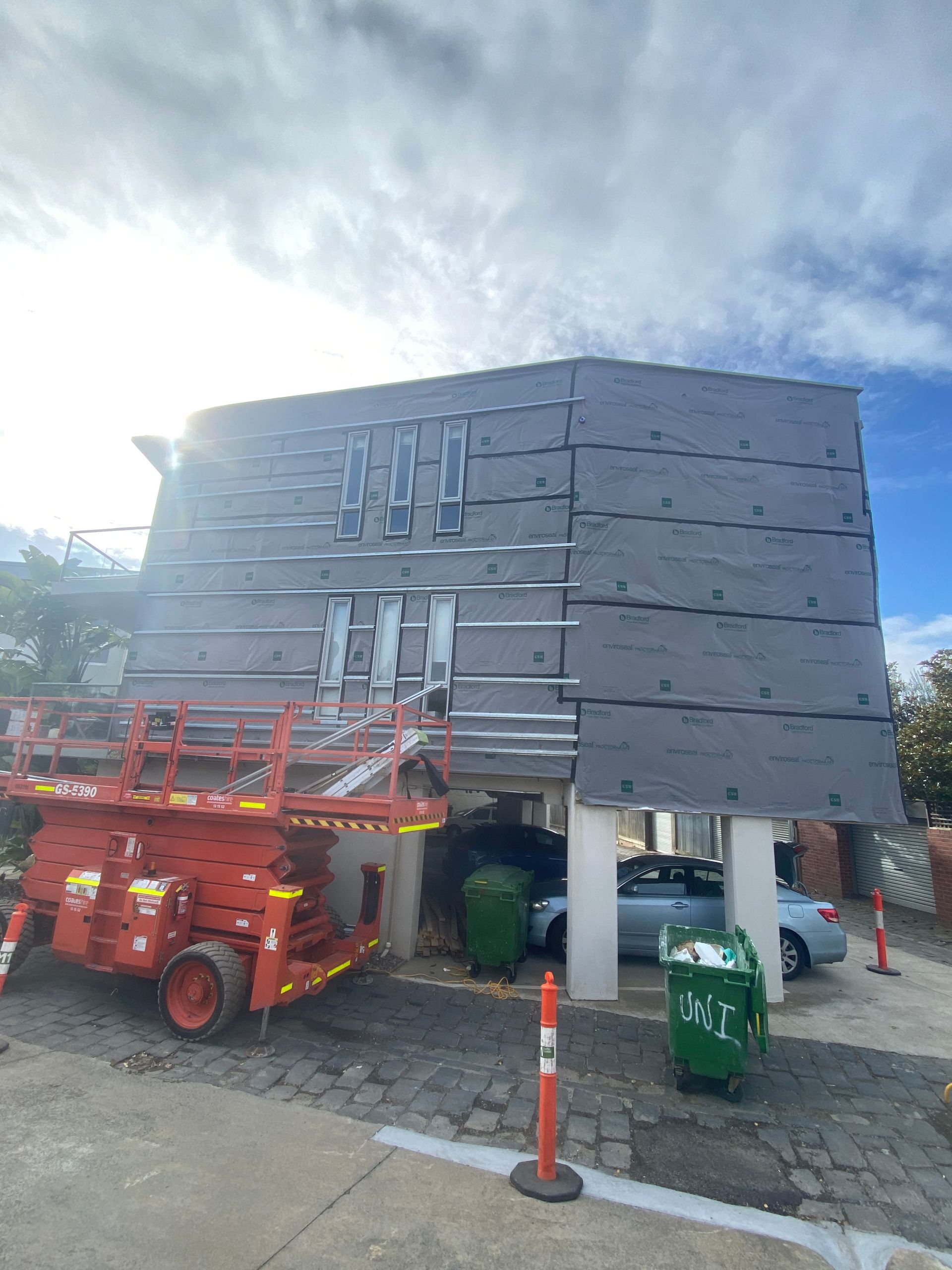 A red scissor lift is parked in front of a building.