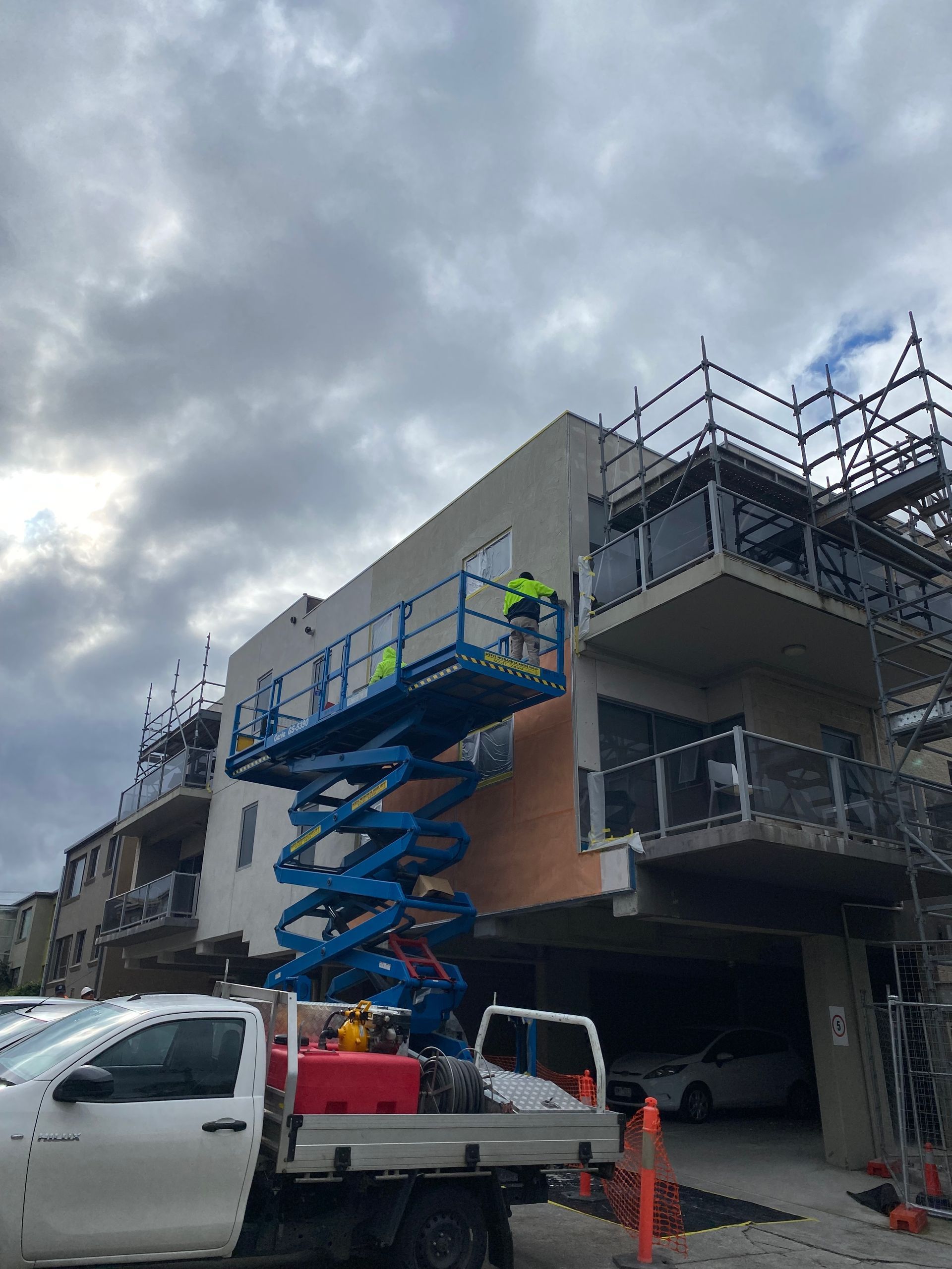 A white truck is parked in front of a building under construction.