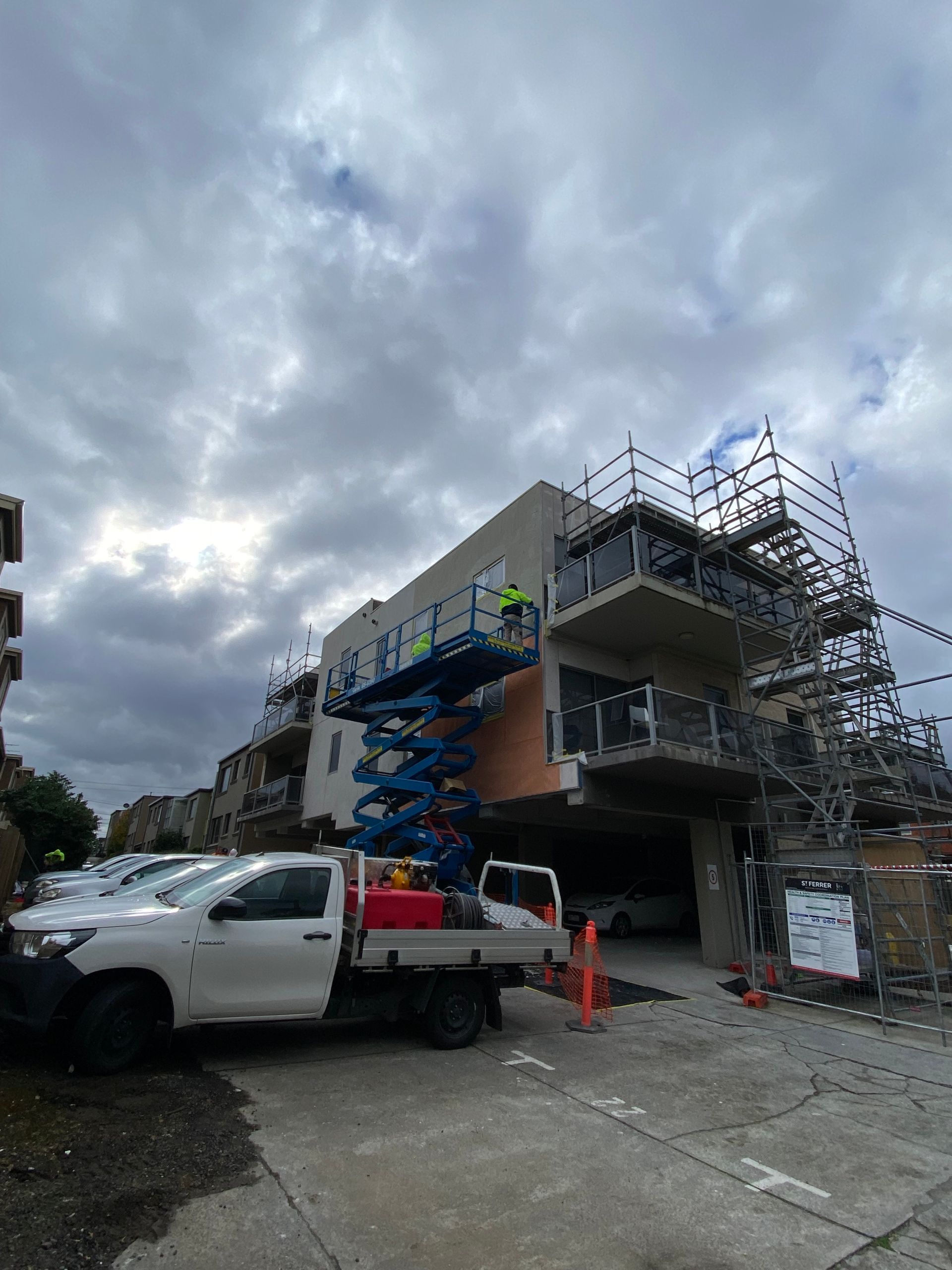 A white truck is parked in front of a building under construction.