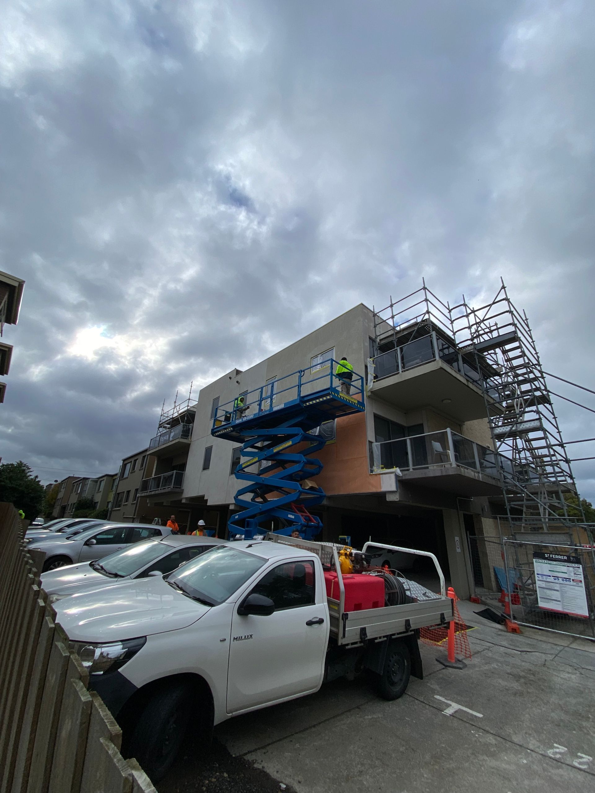 A white truck is parked in front of a building under construction.