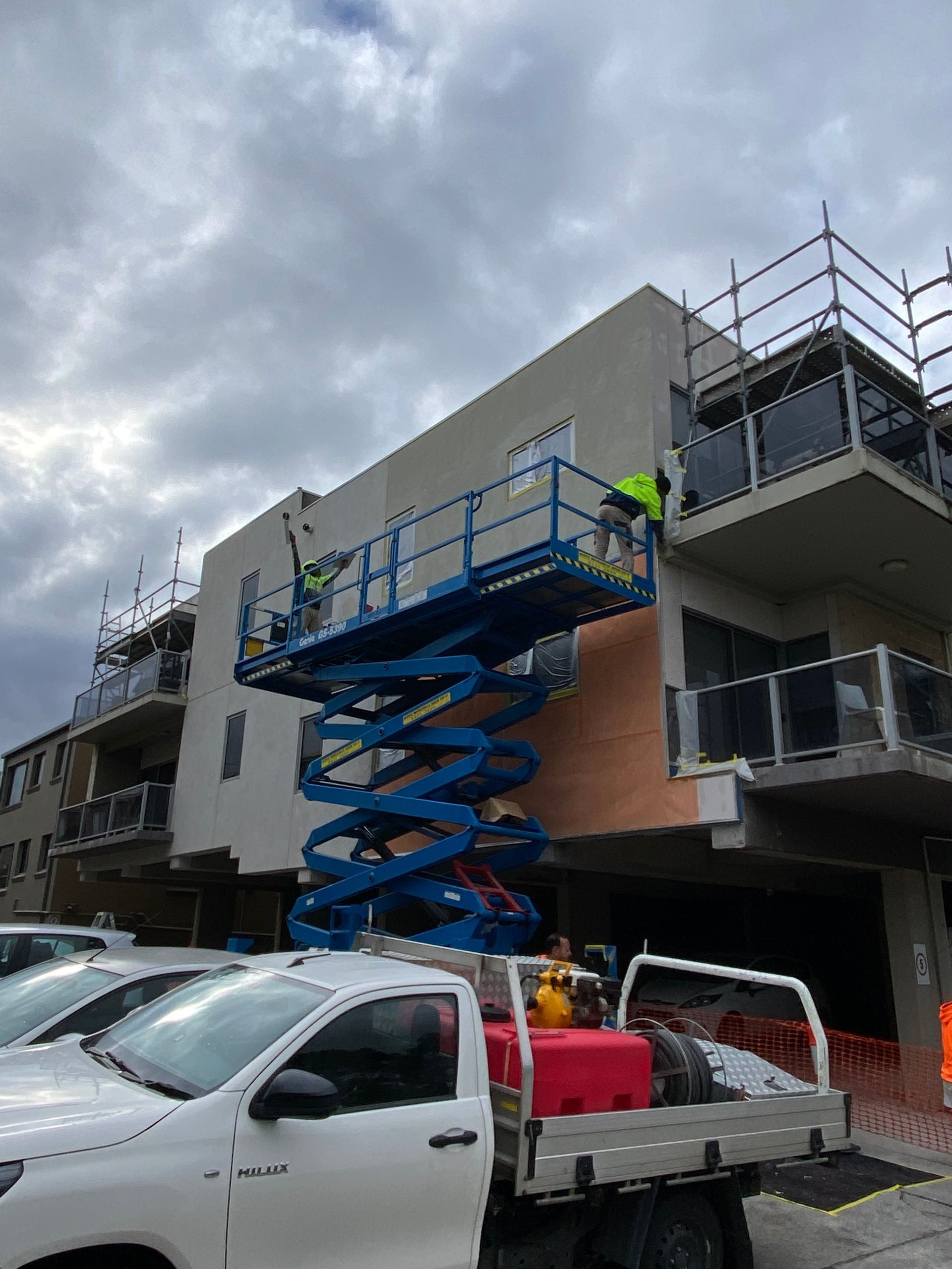 A white truck is parked in front of a building under construction.