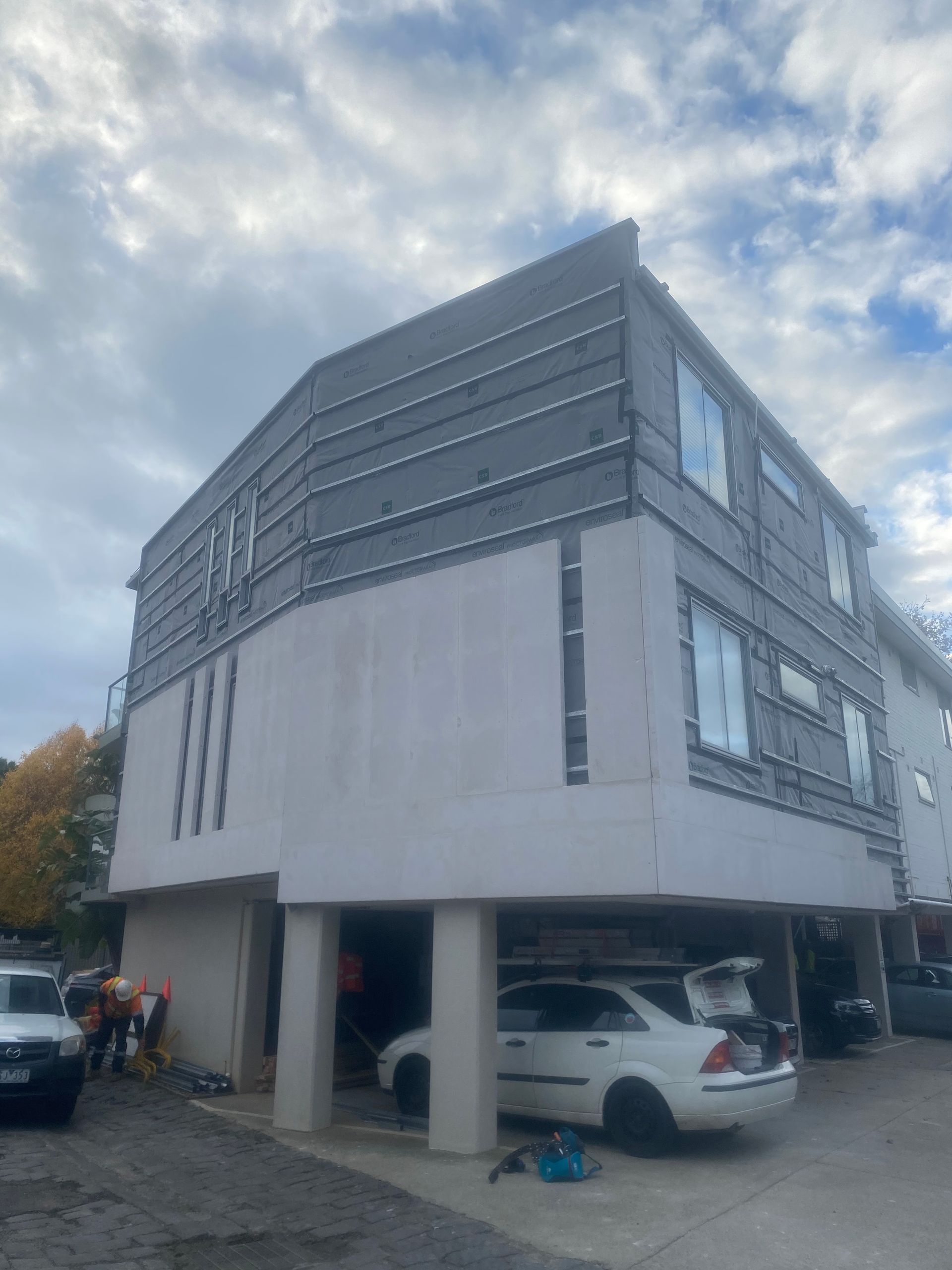 A white car is parked in front of a large building.
