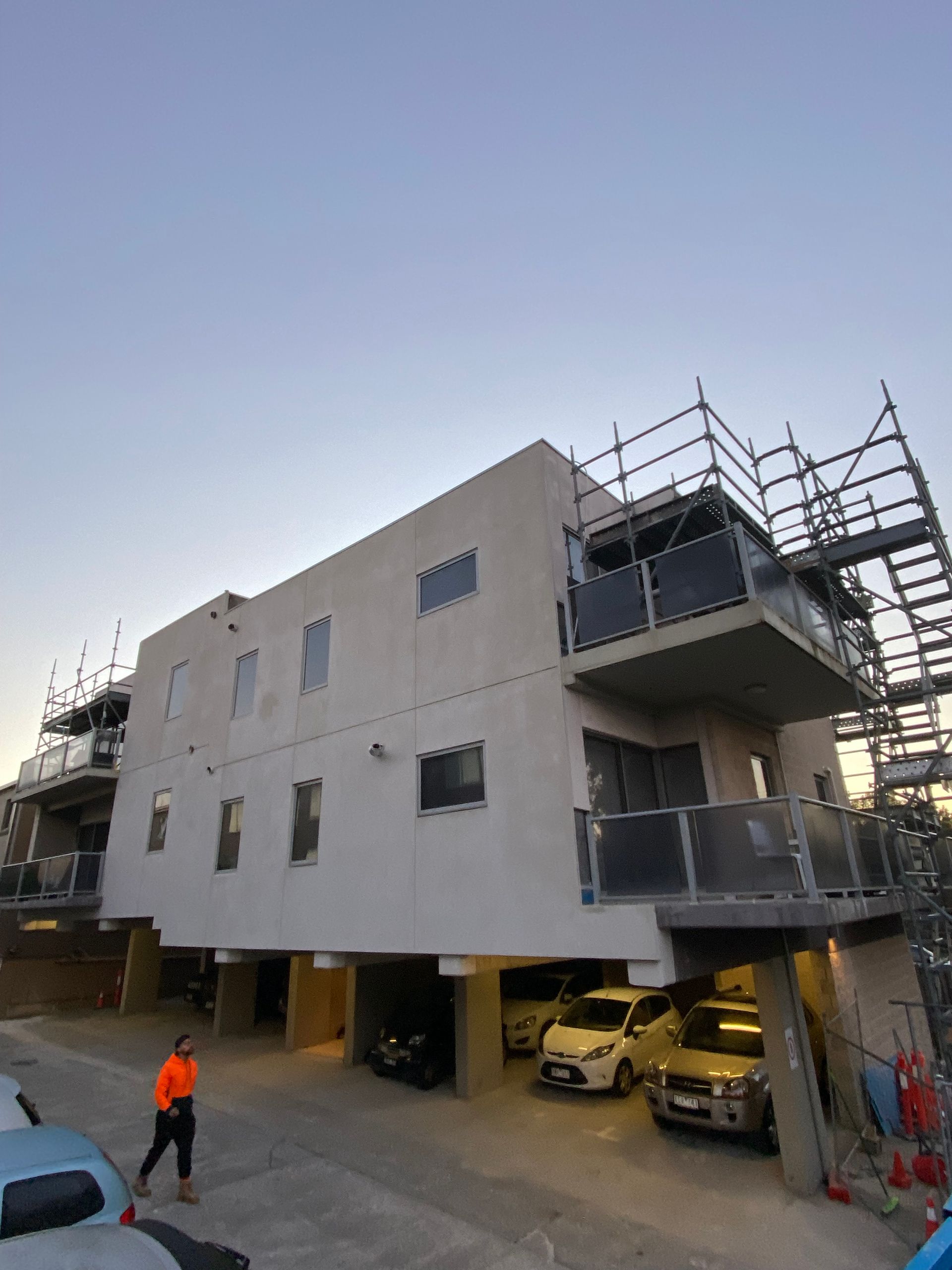 A building under construction with cars parked in front of it