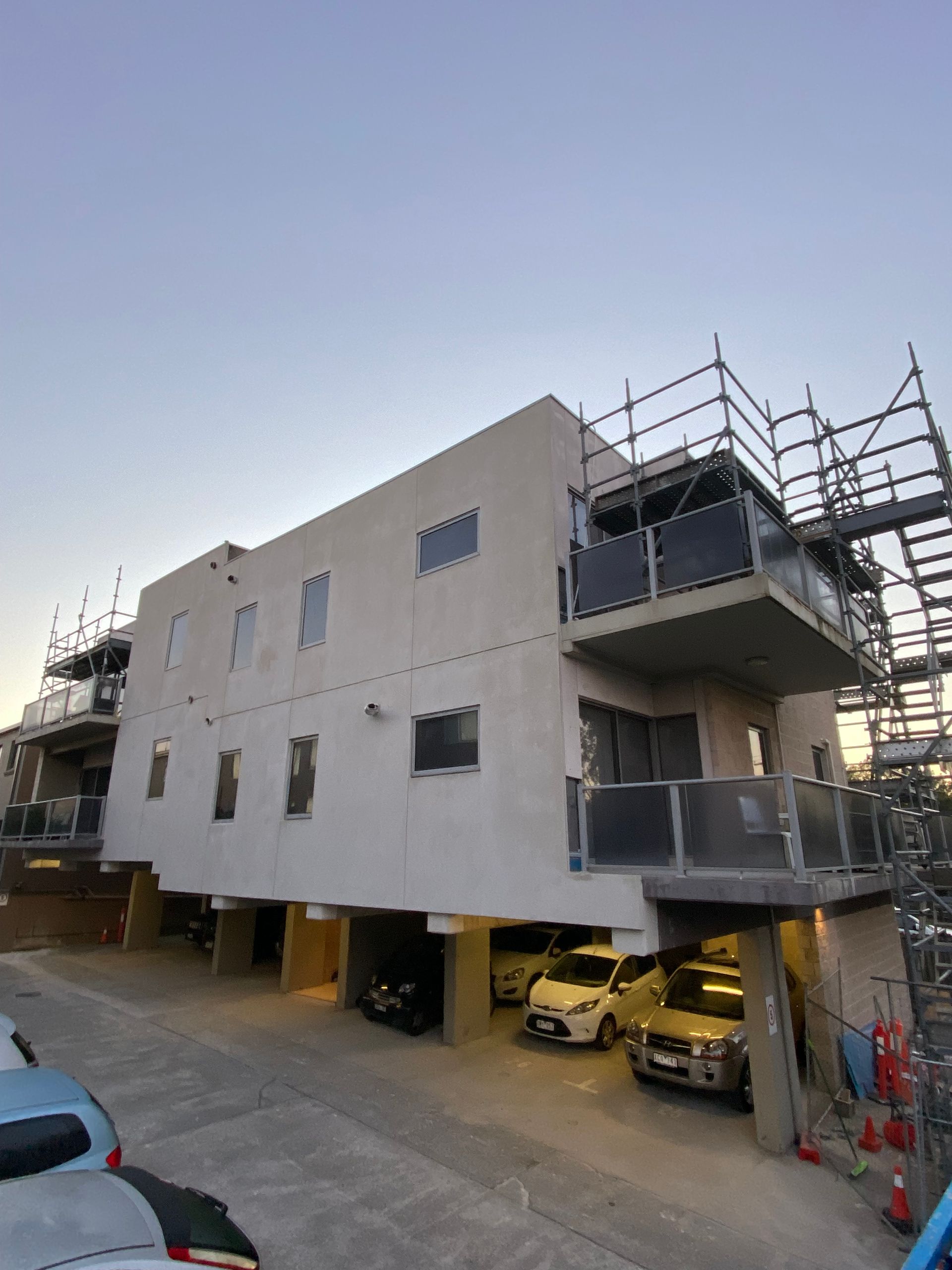 A building under construction with cars parked in front of it