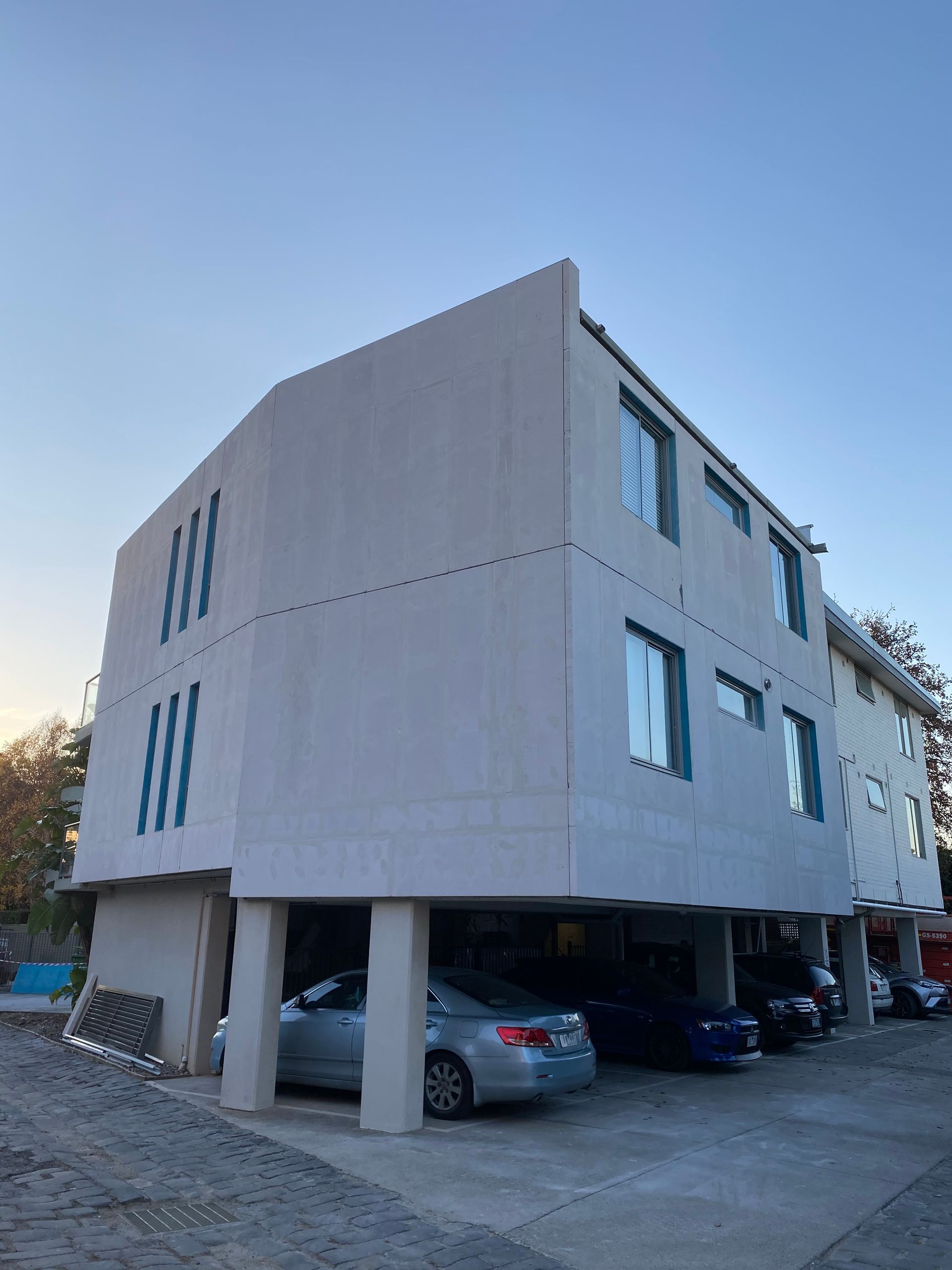 A large white building with cars parked underneath it