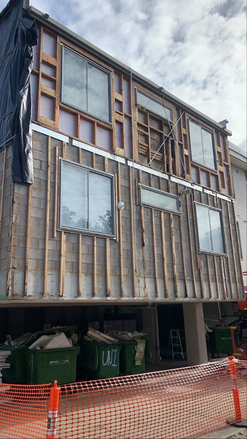 A building under construction with a lot of windows and a fence around it.