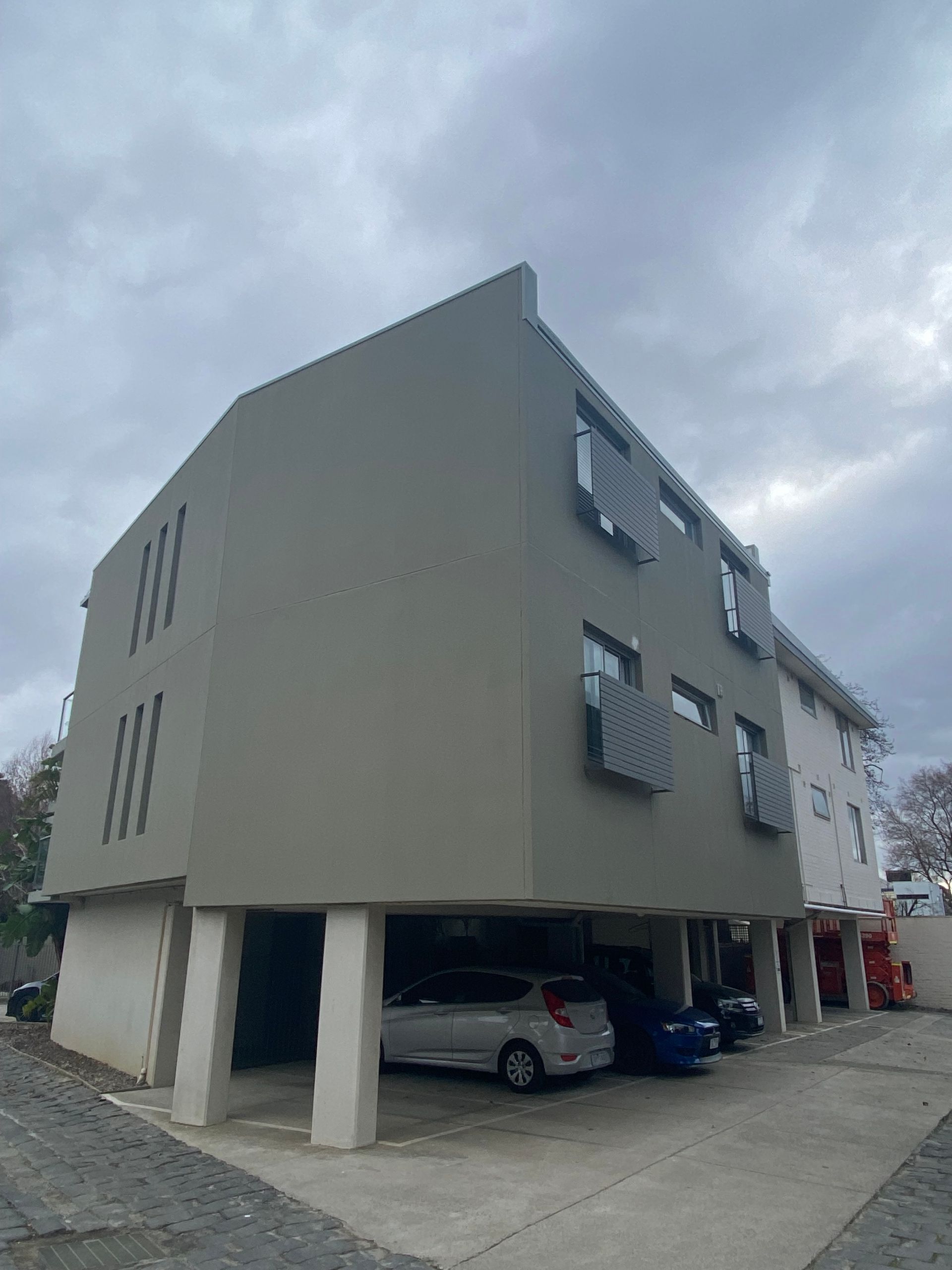 A building with cars parked in front of it on a cloudy day