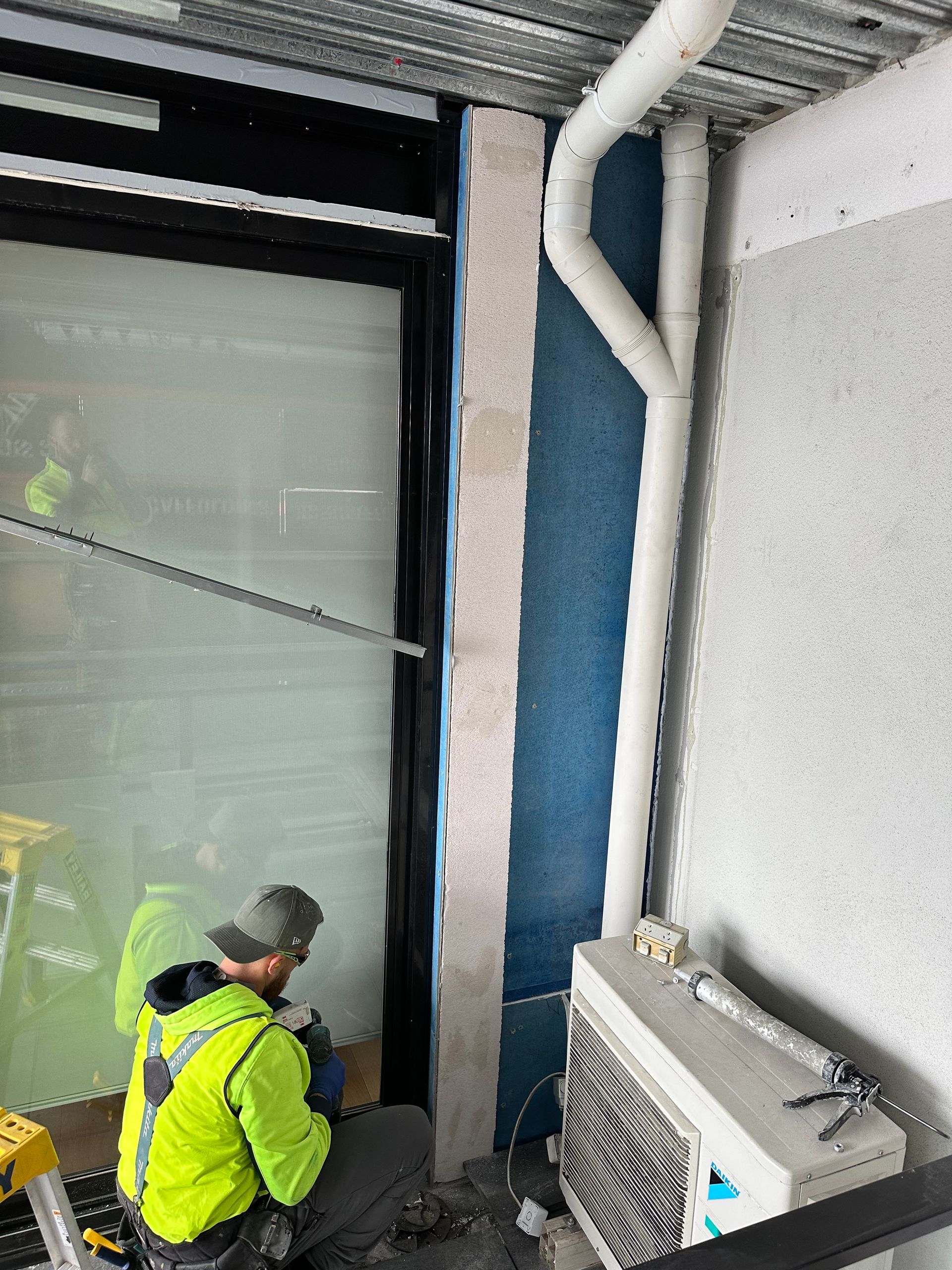 A man in a yellow jacket is working on a window