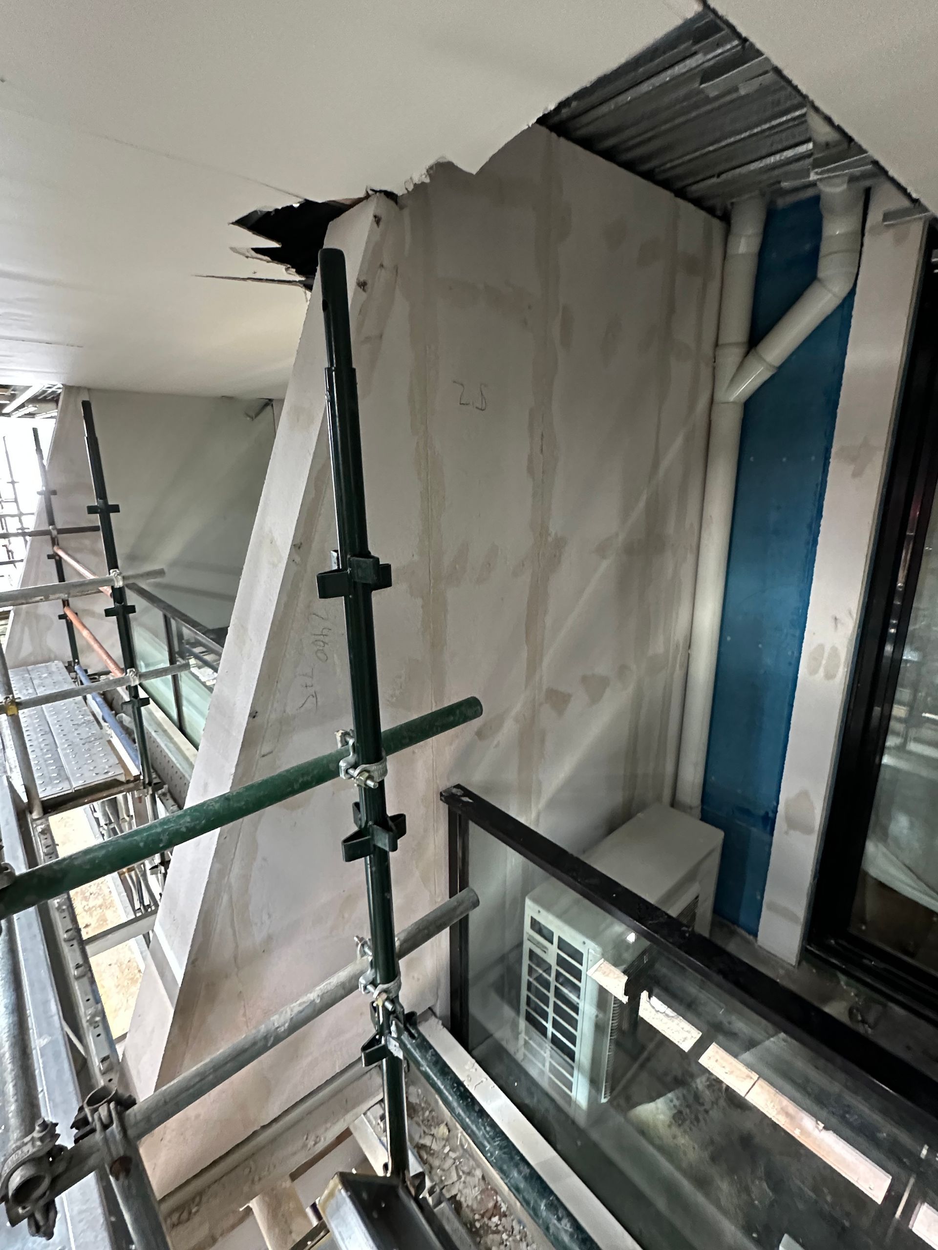 A building under construction with scaffolding and a balcony.