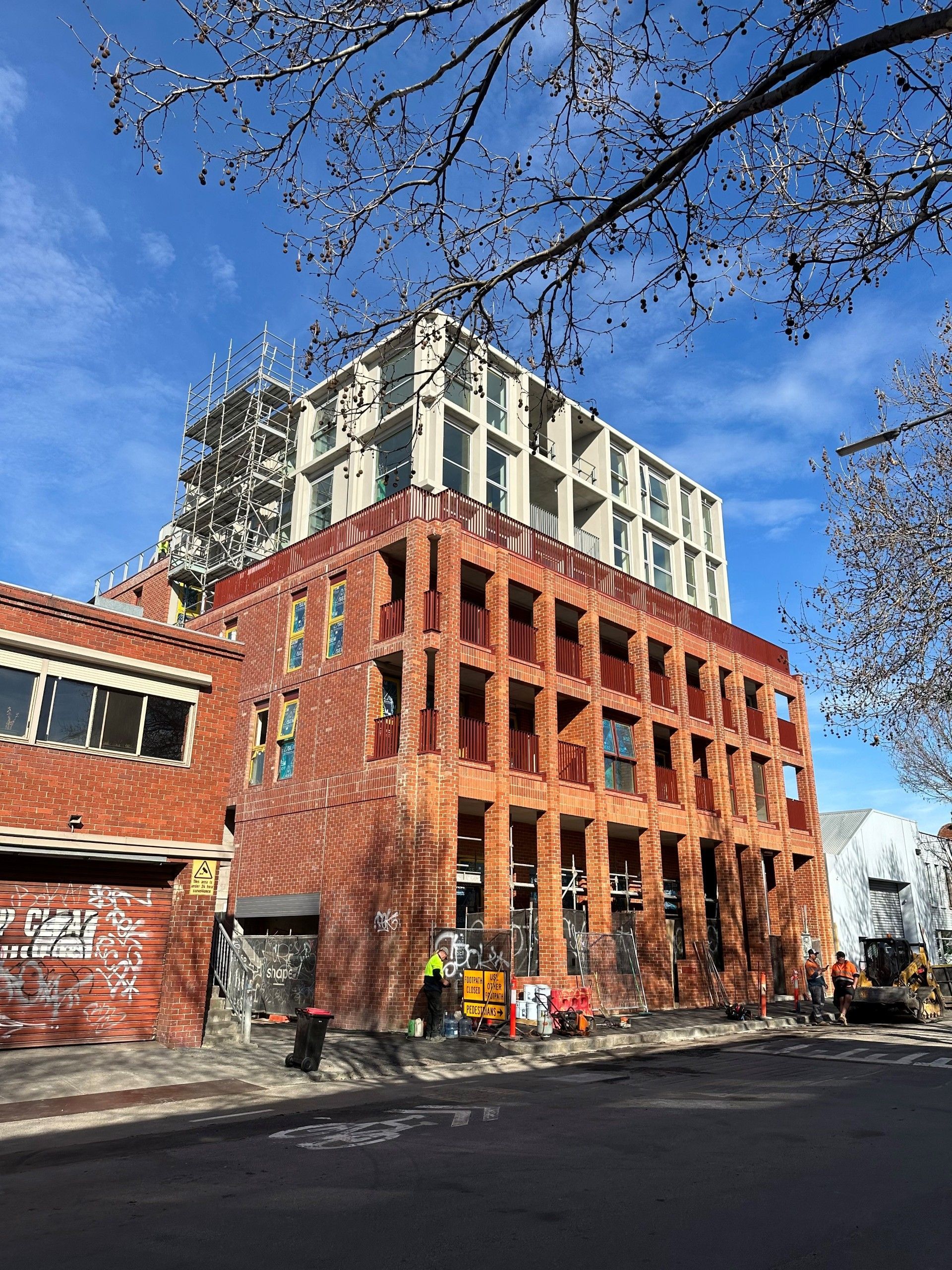 A large brick building is being built on the side of the road.
