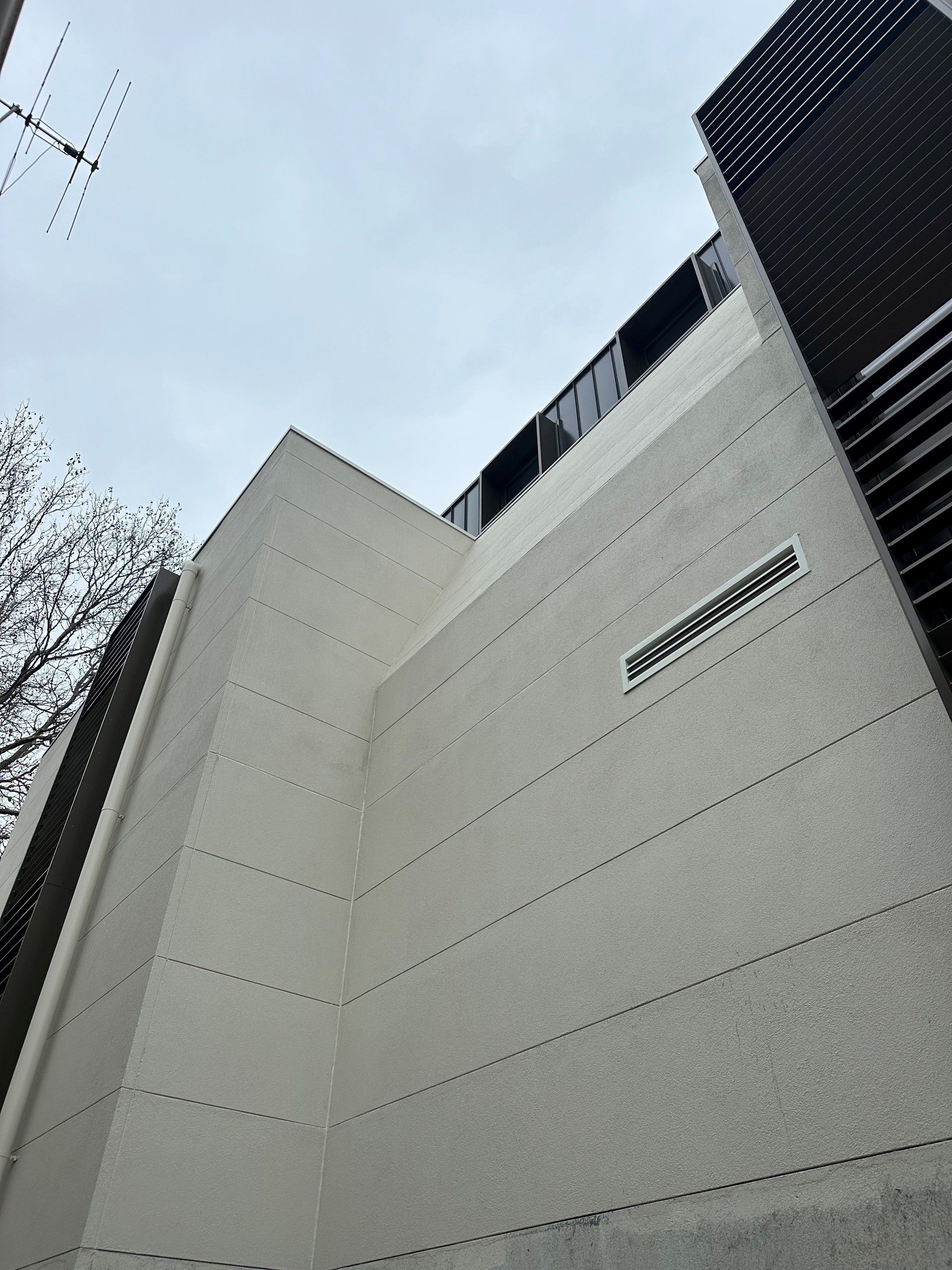Looking up at a tall building with a sign on the side that says ' tokyo '