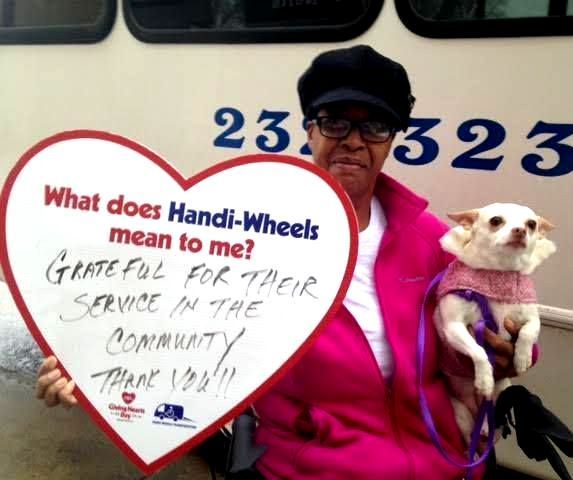 A female holding a heart with these written words: What does Handi-Wheels mean to me? Grateful for their service in the community. Thank you!!