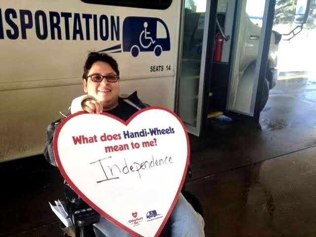 A female holding a heart with these written words:What does Handi-Wheels mean to me? Independence