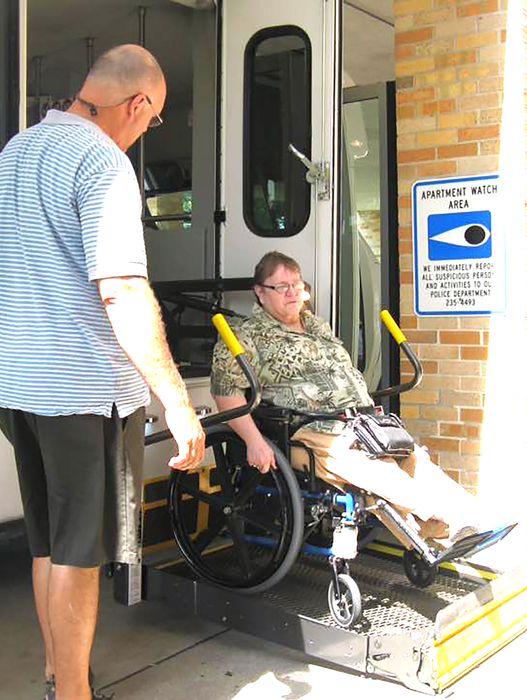 a Handi-Wheels driver loading a wheelchair bound passenger into a Handi-Wheels van