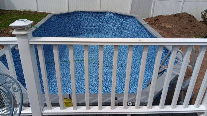 A swimming pool is being built in a backyard next to a white railing.
