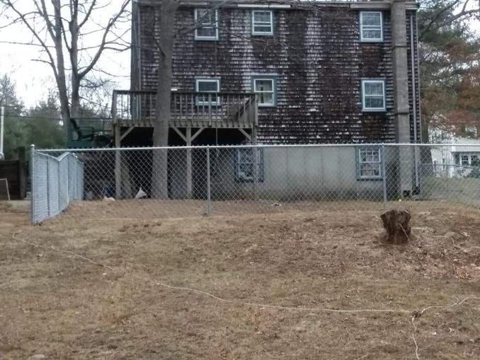 A chain link fence is in front of a large house.