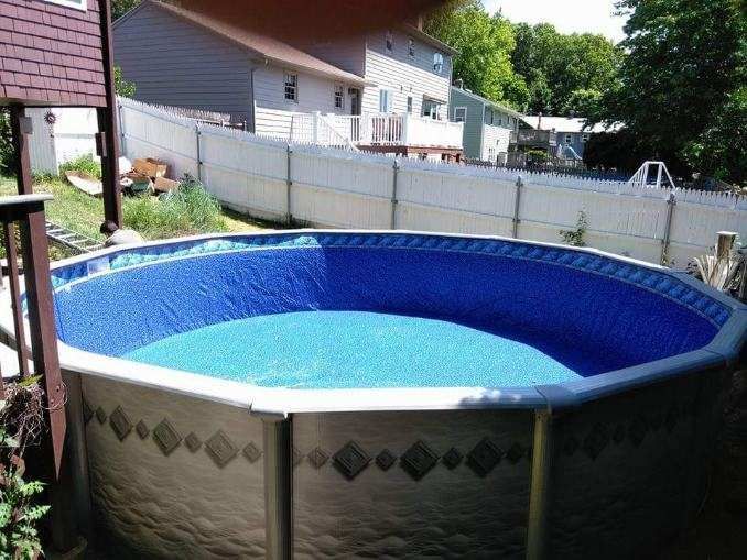 A large swimming pool with a blue liner in a backyard