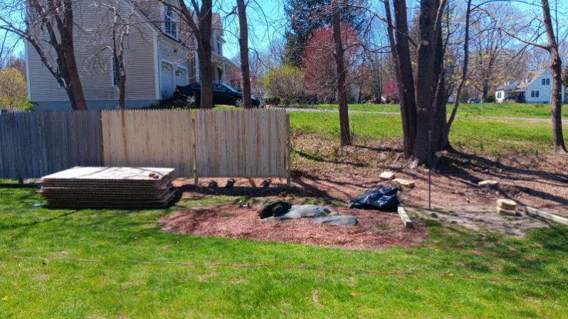 A wooden fence is being built in the backyard of a house.