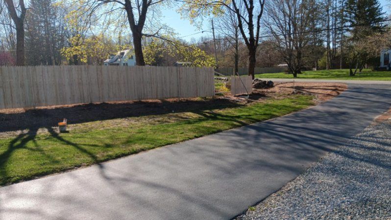 A concrete driveway with a wooden fence along the side of it.