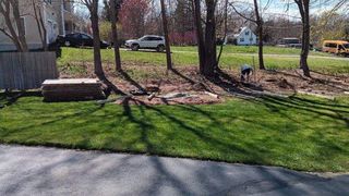 A man is digging in the grass in front of a house.