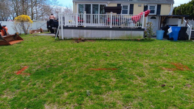 A backyard with a house and a deck in the background.