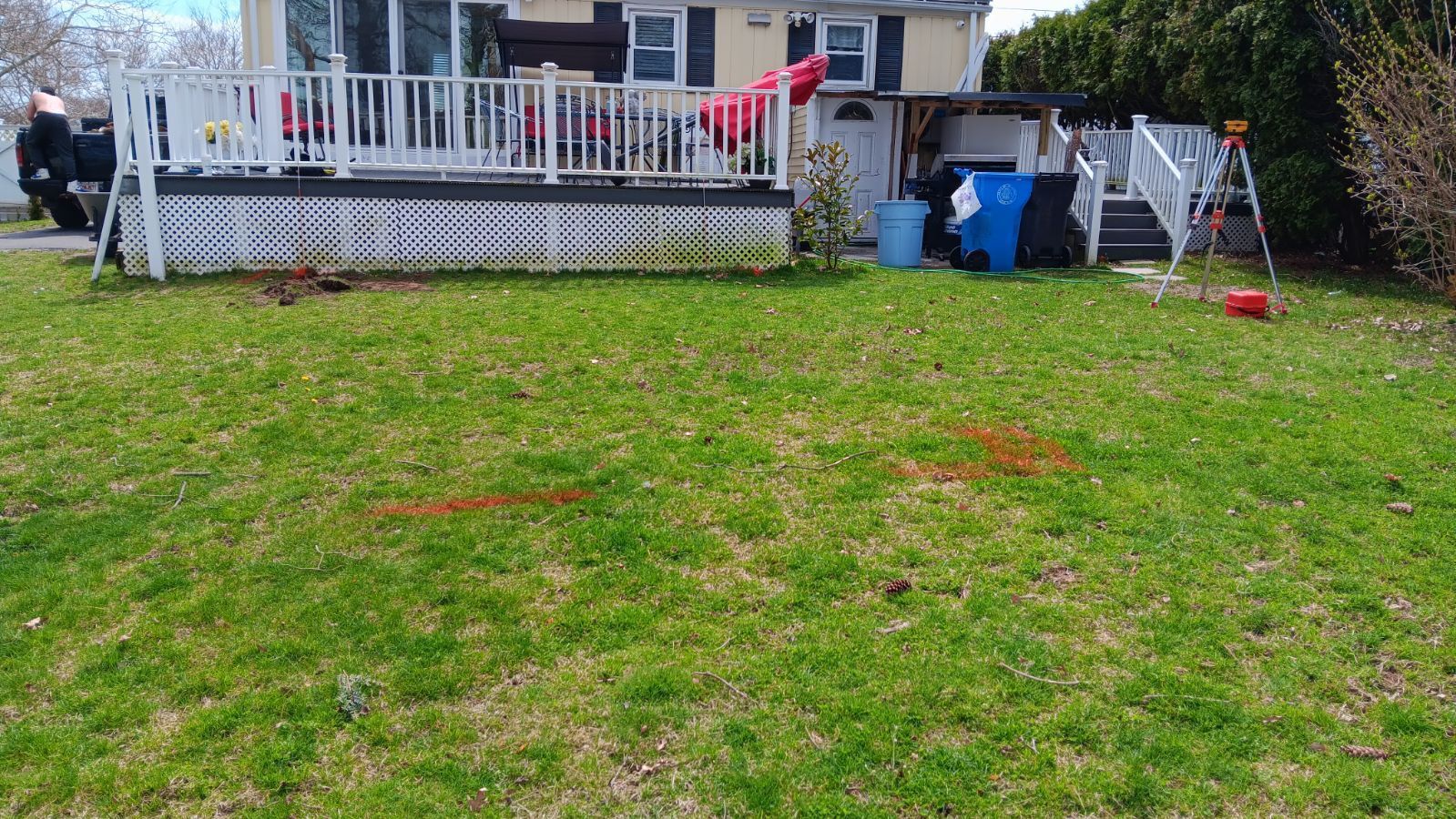 A large lawn in front of a house with a deck.