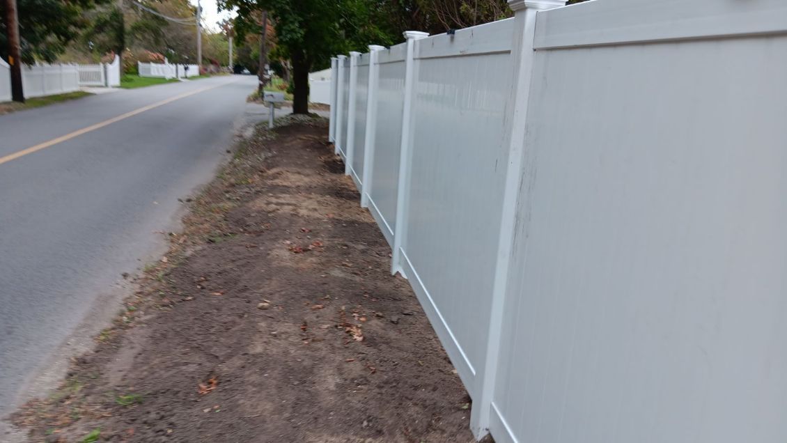 A white fence along the side of a road.