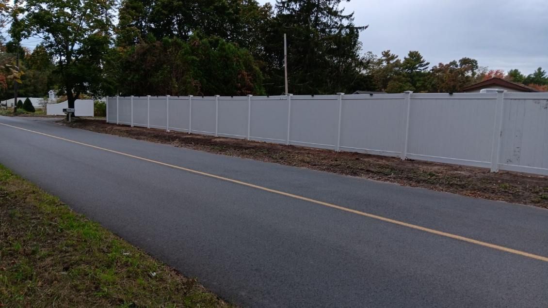 A white fence along the side of a road.