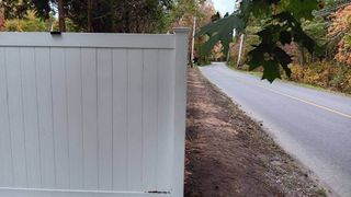 A white fence is along the side of a road.