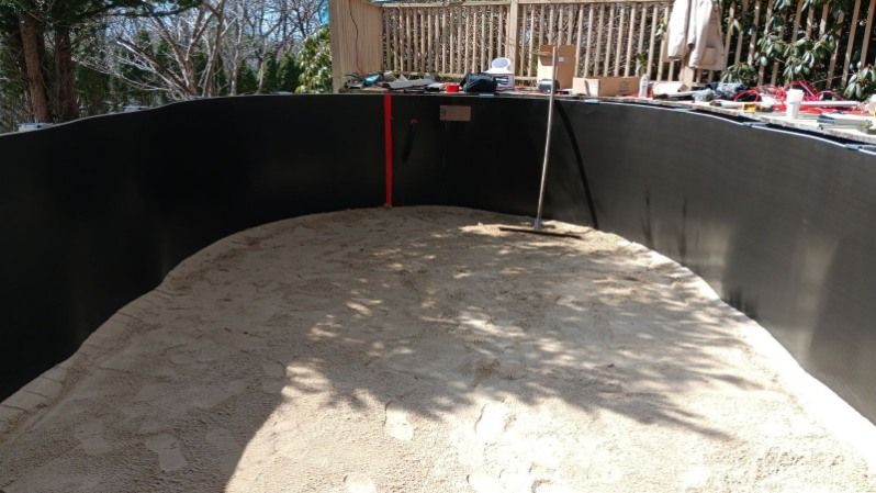 A large pile of sand is sitting in front of a black wall.