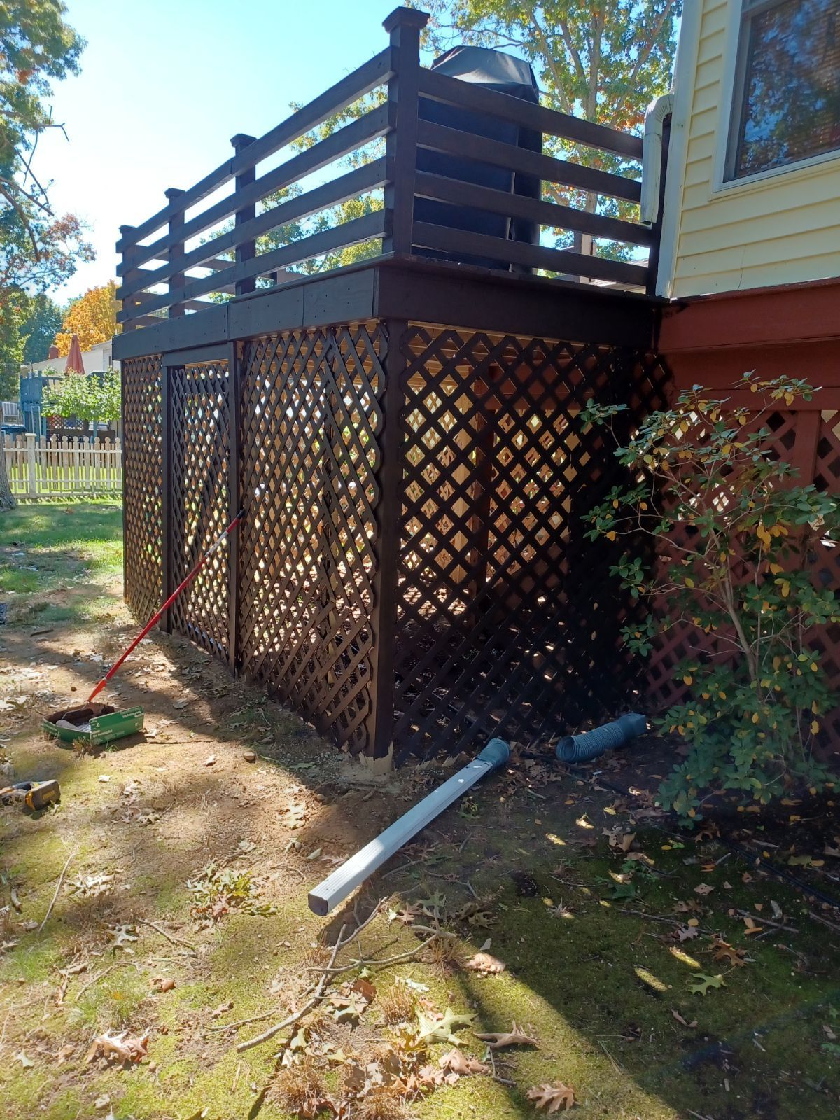 A wooden deck with a lattice fence on the side of a house.