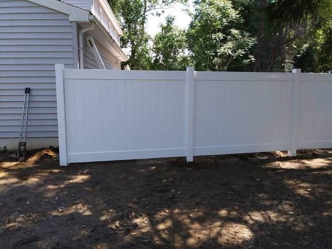 A white fence is sitting in front of a house.
