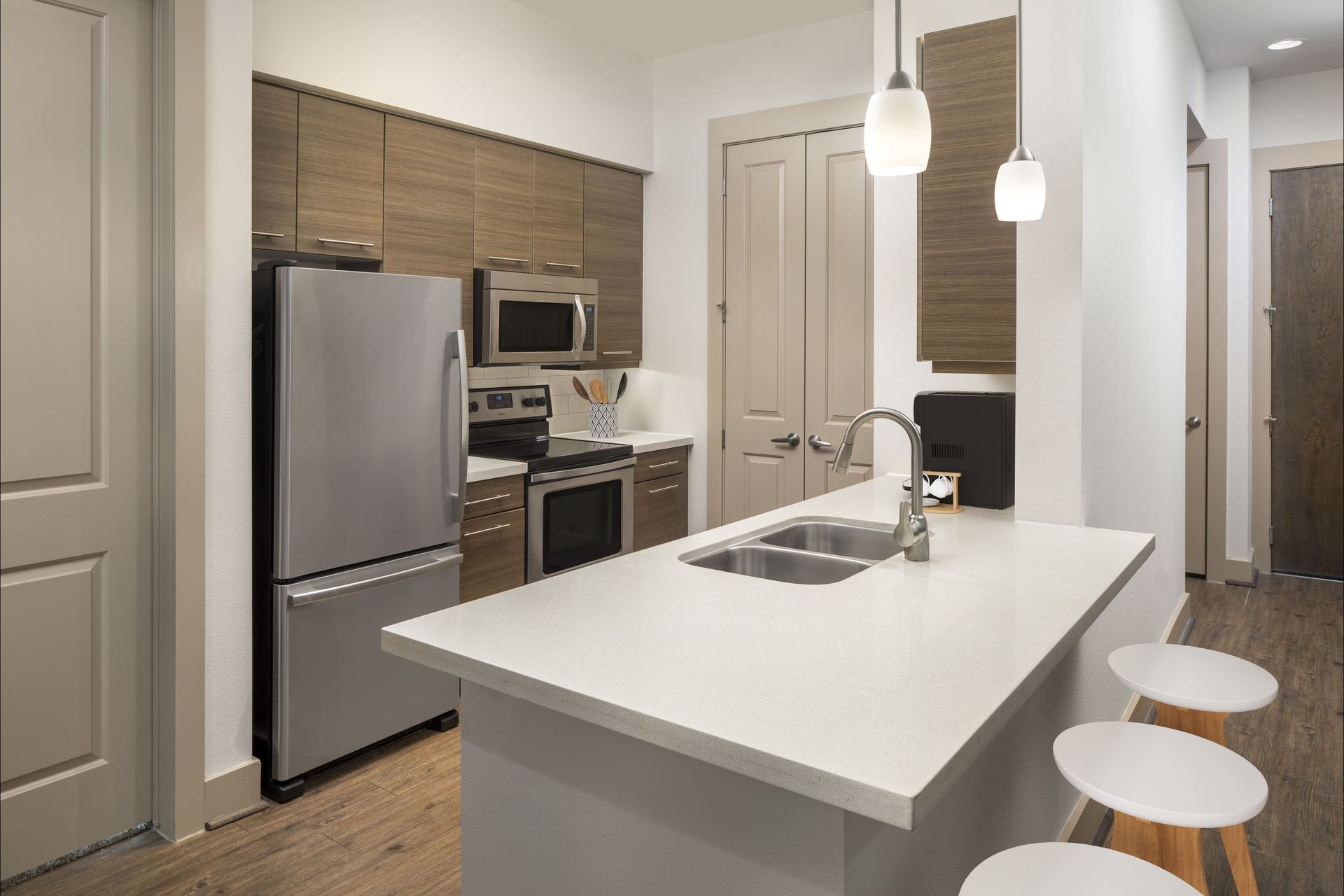 Modern kitchen with stainless steel appliances and bar stools at Marquis Enclave, offers apartments for rent in Midtown Houston, TX.