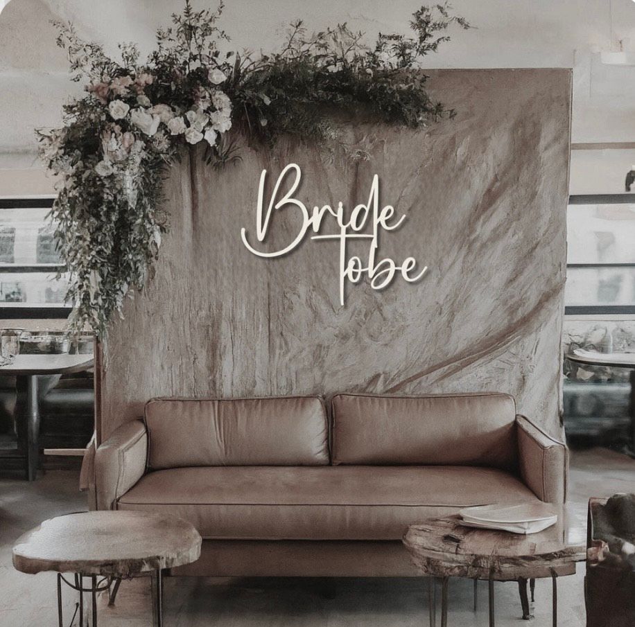 A white trailer is parked in the grass next to a row of chairs and tables.