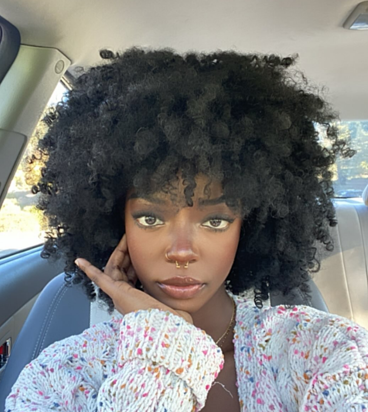 A woman with curly hair is sitting in a car.