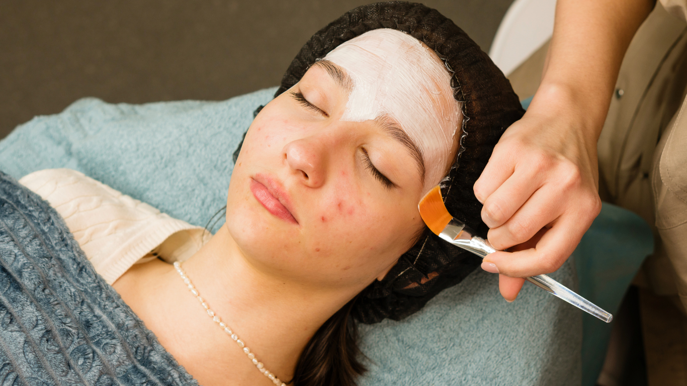 A woman is getting a facial treatment with a brush