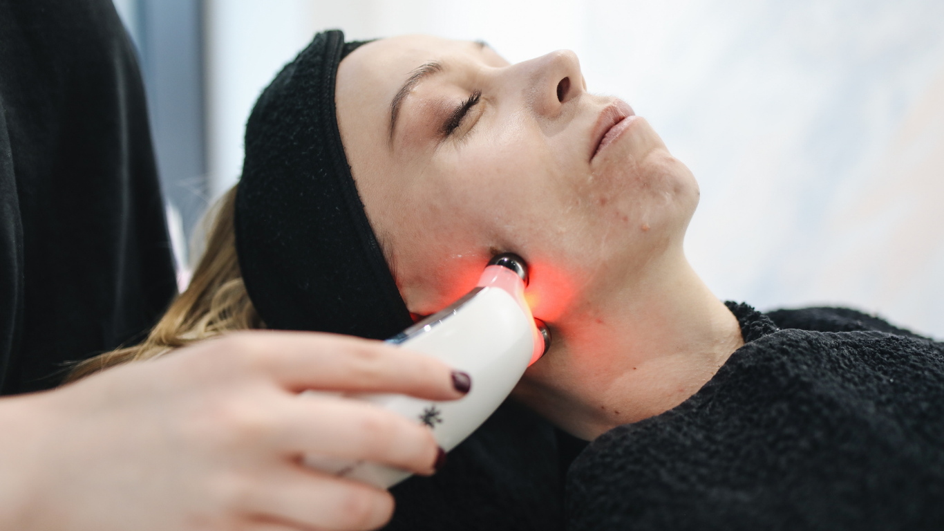 A woman is getting a red light treatment on her face.