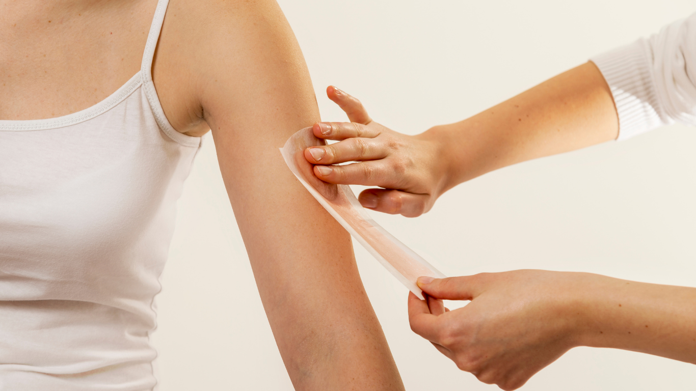 A woman is getting her arm waxed by a woman.