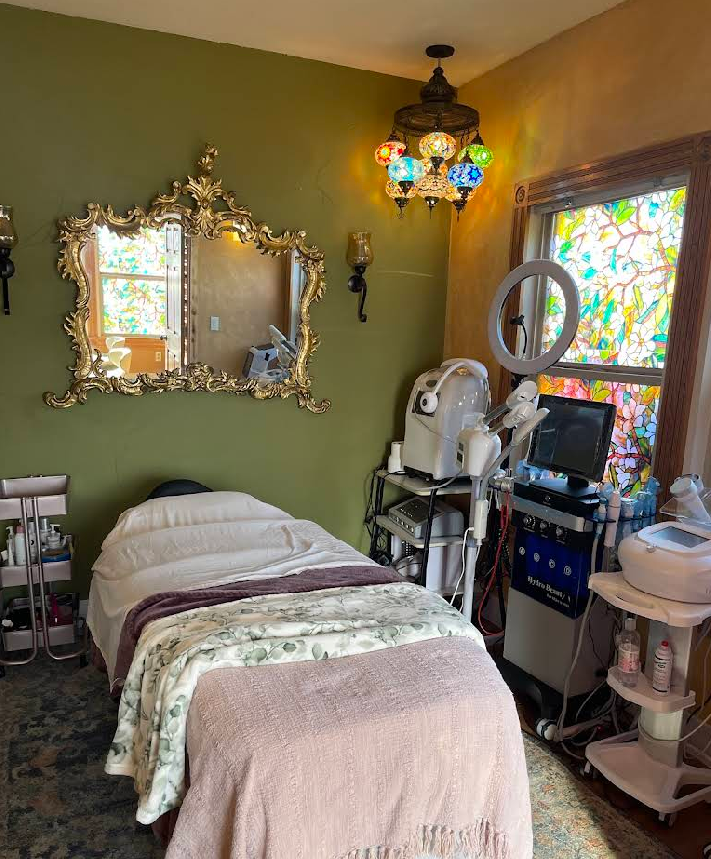 A room with a bed , mirror , and stained glass window.