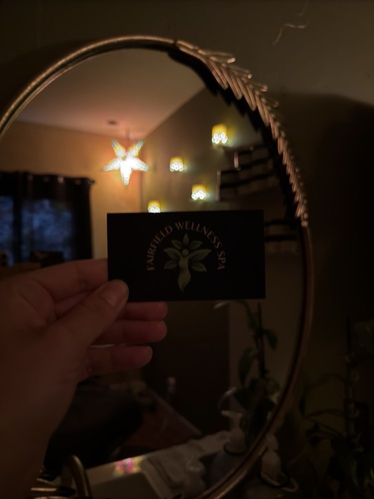 A person holding a card that says emerald wellness in front of a mirror